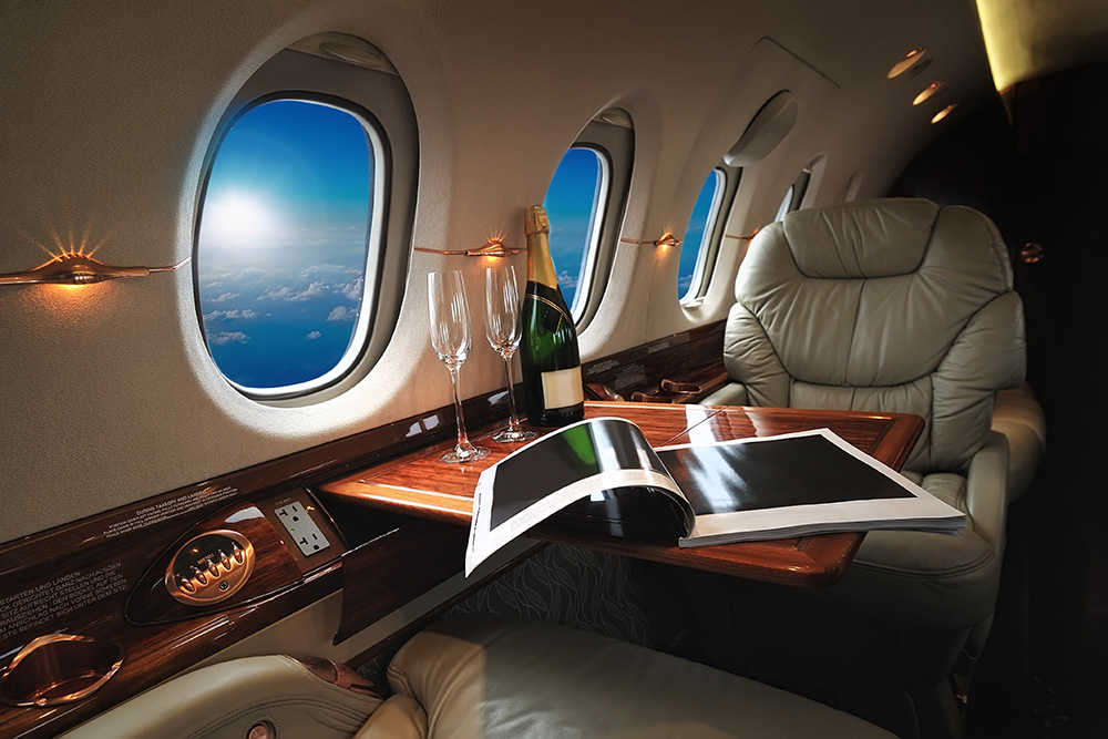 luxury interior in the modern business jet and sunlight at the window/sky and clouds through the porthole