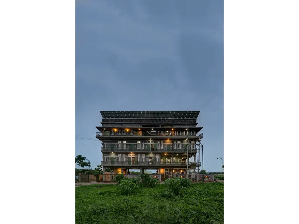 In an era obsessed with glass towers, imported stone, and air-conditioned excess, Chitra Vishwanath did something borderline rebellious: she picked up mud — and built the future. While the architectural world sprinted toward shiny facades and carbon-heavy vanity, she stayed rooted, almost literally, in the soil beneath her feet. Her buildings don’t scream; they exhale. They don’t dominate landscapes; they collaborate with them. And in a city like Bengaluru, where the climate is changing faster than the skyline, Vishwanath’s work is a quiet but powerful reminder that sustainability isn’t a trend. It’s good design with its conscience intact. A Childhood Shaped By Ecology And Curiosity Chitra Vishwanath’s early fascination with nature, resourcefulness, and the quiet intelligence of traditional craft laid the groundwork for her design philosophy. Growing up in an India where nothing was wasted and everything was repurposed, she developed an instinctive understanding that architecture wasn’t about spectacle — it was about function, climate, community, and care. That sensibility would later become the spine of her work. Choosing Earth When The World Chased Concrete By the 1990s, when Indian cities were racing to embrace glass-heavy, imported-material “modernity,” Vishwanath calmly charted a different path. Instead of concrete and metal, she chose mud — specifically, stabilised earth blocks. Her reasoning was both scientific and ethical. Earth has low embodied energy, regulates temperature naturally, and is readily available. It’s recyclable, breathable, and culturally rooted. By building her own Bengaluru home out of earth, she demonstrated that sustainability wasn’t theoretical. It was practical, local, resilient, and affordable. The Science Behind Earthy Aesthetic What looks simple in her buildings is often anything but. Behind the raw textures and warm tones lie sophisticated systems that make the architecture perform beautifully without relying on energy-hungry technologies. Natural ventilation replaces air conditioners. Rainwater harvesting is integrated from the blueprint stage. Greywater loops keep waste out of the sewage system. Traditional building know-how meets contemporary structural engineering. Vishwanath doesn’t beautify sustainability — she operationalises it until it becomes the default, not the exception. Biome Environmental Solutions As A Laboratory Of Ecology At Biome Environmental Solutions, the firm she leads, sustainability isn’t a buzzword — it is the organising principle. Architects work alongside ecologists, hydrologists, and community experts to design buildings, water systems, landscapes, and public infrastructure that function as interconnected ecological units. The firm’s work extends far beyond architecture: groundwater recharge, wetlands revival, wastewater management, and ecological urbanism have become core to its mission. In many ways, Vishwanath is designing ecosystems as much as structures. A Philosophy Rooted In People And Planet Chitra Vishwanath’s architecture consistently places human comfort, material honesty, and environmental responsibility above visual theatrics. Her buildings are modest in scale, deeply functional, cost-conscious, and free of ego. She believes that beauty emerges naturally when a structure responds intelligently to climate, culture, and context. Her aesthetic — warm, tactile, grounded — is a byproduct of those values rather than a stylistic ambition. Challenging The Illusion That Modern Means Glass In rapidly urbanising cities, the idea of “modern” architecture is often equated with sealed buildings, reflective facades, and mechanical cooling systems. Vishwanath dismantles that notion with precision. To her, modernity is measured by intelligence, not appearance. A building is modern if it consumes less energy, interacts with natural forces, manages its water responsibly, uses local materials, and leaves a small ecological footprint. Her definition resets the conversation — and it’s one the climate desperately needs. Projects That Shifted The Sustainability Conversation Several of Vishwanath’s projects have become touchstones in India’s sustainable architecture movement. Her own residence and office demonstrate how an urban building can be almost entirely self-sufficient. Schools and community structures she has designed show the scalability of earth architecture. Her water-sensitive urban planning projects have influenced how neighbourhoods and cities view groundwater, stormwater, and sewage. Each project becomes a case study, not only in design but in ecological logic. Craftspeople As Partners In Innovation A crucial, often overlooked dimension of her work is the role of skilled masons and craftspeople. Vishwanath treats them not as labourers but as co-creators. Their knowledge of traditional construction techniques and material behaviour becomes as essential as the architect’s drawings. On her sites, learning flows in every direction — craftspeople adopt new scientific methods, and architects gain insight from centuries-old skills. This collaborative ecosystem strengthens livelihoods while keeping traditional craftsmanship alive. A Legacy That Offers India A Blueprint For Resilience In a country facing climate unpredictability, water scarcity, and urban stress, Chitra Vishwanath’s work stands as a blueprint for the future. Her designs prove that sustainability isn’t a compromise — it’s an upgrade. She has shown that buildings can be cost-effective, climate-responsive, culturally rooted, and aesthetically compelling without exhausting the planet. Her legacy is not just architectural. It is ecological, social, and systemic. By choosing earth, she gave Indian architecture something far more enduring than a style — she gave it a conscience