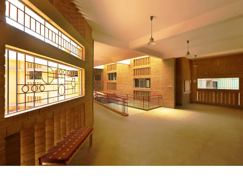 In an era obsessed with glass towers, imported stone, and air-conditioned excess, Chitra Vishwanath did something borderline rebellious: she picked up mud — and built the future. While the architectural world sprinted toward shiny facades and carbon-heavy vanity, she stayed rooted, almost literally, in the soil beneath her feet. Her buildings don’t scream; they exhale. They don’t dominate landscapes; they collaborate with them. And in a city like Bengaluru, where the climate is changing faster than the skyline, Vishwanath’s work is a quiet but powerful reminder that sustainability isn’t a trend. It’s good design with its conscience intact. A Childhood Shaped By Ecology And Curiosity Chitra Vishwanath’s early fascination with nature, resourcefulness, and the quiet intelligence of traditional craft laid the groundwork for her design philosophy. Growing up in an India where nothing was wasted and everything was repurposed, she developed an instinctive understanding that architecture wasn’t about spectacle — it was about function, climate, community, and care. That sensibility would later become the spine of her work. Choosing Earth When The World Chased Concrete By the 1990s, when Indian cities were racing to embrace glass-heavy, imported-material “modernity,” Vishwanath calmly charted a different path. Instead of concrete and metal, she chose mud — specifically, stabilised earth blocks. Her reasoning was both scientific and ethical. Earth has low embodied energy, regulates temperature naturally, and is readily available. It’s recyclable, breathable, and culturally rooted. By building her own Bengaluru home out of earth, she demonstrated that sustainability wasn’t theoretical. It was practical, local, resilient, and affordable. The Science Behind Earthy Aesthetic What looks simple in her buildings is often anything but. Behind the raw textures and warm tones lie sophisticated systems that make the architecture perform beautifully without relying on energy-hungry technologies. Natural ventilation replaces air conditioners. Rainwater harvesting is integrated from the blueprint stage. Greywater loops keep waste out of the sewage system. Traditional building know-how meets contemporary structural engineering. Vishwanath doesn’t beautify sustainability — she operationalises it until it becomes the default, not the exception. Biome Environmental Solutions As A Laboratory Of Ecology At Biome Environmental Solutions, the firm she leads, sustainability isn’t a buzzword — it is the organising principle. Architects work alongside ecologists, hydrologists, and community experts to design buildings, water systems, landscapes, and public infrastructure that function as interconnected ecological units. The firm’s work extends far beyond architecture: groundwater recharge, wetlands revival, wastewater management, and ecological urbanism have become core to its mission. In many ways, Vishwanath is designing ecosystems as much as structures. A Philosophy Rooted In People And Planet Chitra Vishwanath’s architecture consistently places human comfort, material honesty, and environmental responsibility above visual theatrics. Her buildings are modest in scale, deeply functional, cost-conscious, and free of ego. She believes that beauty emerges naturally when a structure responds intelligently to climate, culture, and context. Her aesthetic — warm, tactile, grounded — is a byproduct of those values rather than a stylistic ambition. Challenging The Illusion That Modern Means Glass In rapidly urbanising cities, the idea of “modern” architecture is often equated with sealed buildings, reflective facades, and mechanical cooling systems. Vishwanath dismantles that notion with precision. To her, modernity is measured by intelligence, not appearance. A building is modern if it consumes less energy, interacts with natural forces, manages its water responsibly, uses local materials, and leaves a small ecological footprint. Her definition resets the conversation — and it’s one the climate desperately needs. Projects That Shifted The Sustainability Conversation Several of Vishwanath’s projects have become touchstones in India’s sustainable architecture movement. Her own residence and office demonstrate how an urban building can be almost entirely self-sufficient. Schools and community structures she has designed show the scalability of earth architecture. Her water-sensitive urban planning projects have influenced how neighbourhoods and cities view groundwater, stormwater, and sewage. Each project becomes a case study, not only in design but in ecological logic. Craftspeople As Partners In Innovation A crucial, often overlooked dimension of her work is the role of skilled masons and craftspeople. Vishwanath treats them not as labourers but as co-creators. Their knowledge of traditional construction techniques and material behaviour becomes as essential as the architect’s drawings. On her sites, learning flows in every direction — craftspeople adopt new scientific methods, and architects gain insight from centuries-old skills. This collaborative ecosystem strengthens livelihoods while keeping traditional craftsmanship alive. A Legacy That Offers India A Blueprint For Resilience In a country facing climate unpredictability, water scarcity, and urban stress, Chitra Vishwanath’s work stands as a blueprint for the future. Her designs prove that sustainability isn’t a compromise — it’s an upgrade. She has shown that buildings can be cost-effective, climate-responsive, culturally rooted, and aesthetically compelling without exhausting the planet. Her legacy is not just architectural. It is ecological, social, and systemic. By choosing earth, she gave Indian architecture something far more enduring than a style — she gave it a conscience.