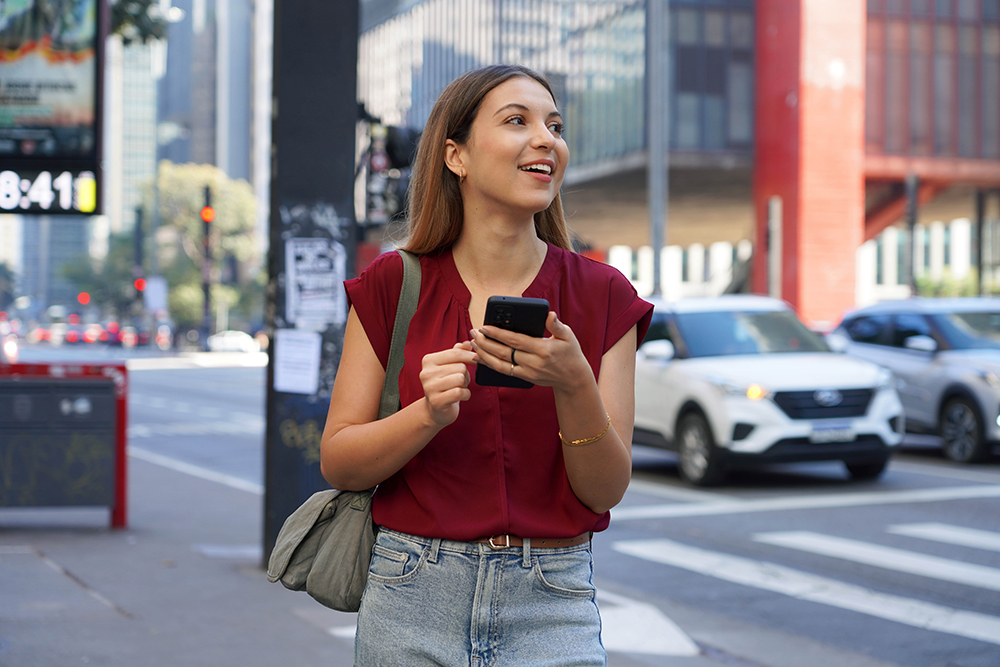 chauffeur service Uber - Close-up of Brazilian business woman hail a vehicle using mobile app